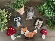 small crocheted animals sitting on top of a wooden table next to plants and flowers