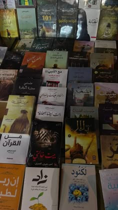 many books are stacked on top of each other with arabic writing and pictures behind them