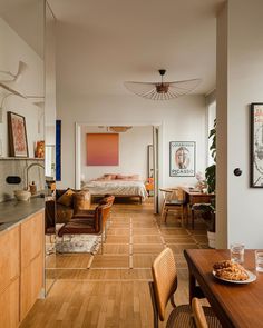 a living room filled with furniture next to a kitchen and dining room table in front of a mirror