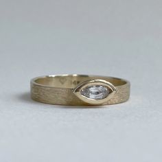 a yellow gold ring with a pear shaped diamond in the center, on a white background