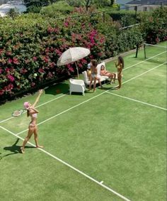 two women are playing tennis on the grass with one holding an umbrella over her head