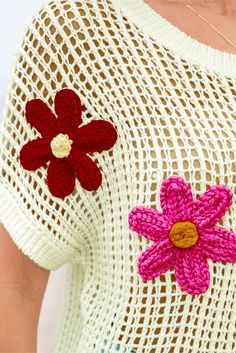 a woman wearing a crochet top with flowers on it