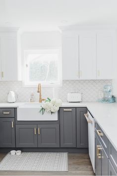 a kitchen with gray cabinets and white counter tops, gold pulls on the faucet