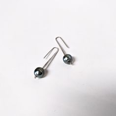 These sterling and Tahitian pearl drops are a your new everyday, minimalist elegant earring. Fabricated from one piece of tapered sterling silver that gives the pearl slight movement. They are light weight, go with everything, and make a lovely gift. Shipped in a branded fabric pouch and jewelry box. Dimensions: Tahitian Pearls: 9mm-11mm Short Drops: 1 5/16" / 33mm Medium Drops: 1.75" / 55mm Handcrafted by Rebecca Norman 2 medium + 2 long in stock and available to ship Minimalist Single Pearl Earring In White Gold, Silver Minimalist Pierced Pearl Earrings, Minimalist Long Drop Earrings With Pearl Charm, Minimalist Long Drop Pearl Earrings With Ear Wire, Minimalist Teardrop Pearl Pendant Earrings, Minimalist Teardrop Pearl Earrings With Ear Wire, Minimalist White Gold Pearl Earrings With Ear Wire, Formal Minimalist Long Drop Pearl Earrings, Formal Long Drop Pearl Earrings Minimalist Style