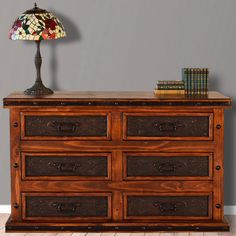 a wooden dresser sitting next to a lamp on top of a hard wood floor