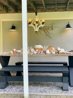 a table with pumpkins and gourds on it in front of a white brick wall