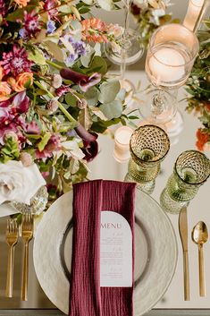 the table is set with silverware, napkins, and flowers in vases