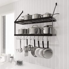 an organized kitchen with pots and pans hanging from the wall, along with utensils