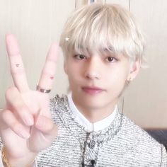 a young man making the peace sign with his fingers