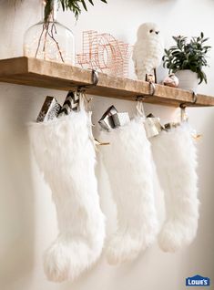 three white christmas stockings hanging from a wooden shelf