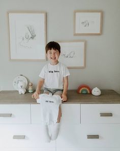 a young boy sitting on top of a dresser