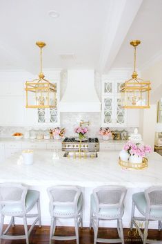 a kitchen with white counter tops and gold chandelier hanging from the ceiling above it