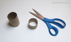 a pair of blue scissors sitting next to a roll of toilet paper and a cup