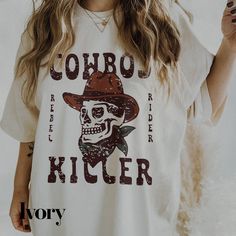 Elevate your country style with our Cowboy Killer Shirt from The Southern Thistle! This western graphic tee features a retro cowboy design that's perfect for any country concert or casual day out. The cute and unique print is sure to turn heads and make a statement.  To maintain the quality of this shirt, we recommend washing it inside out in cold water and laying it flat to dry. If you prefer to use a dryer, make sure to turn the shirt inside out and use the lowest heat setting.  We love creating unique products for our customers, so if you're looking for a custom design, don't hesitate to reach out to us at info@thesouthernthistle.com. We'll work with you to bring your ideas to life.  The Southern Thistle takes pride in our fast processing time of 3-10 business days from the date of your Graphic Print Crew Neck T-shirt For Country Concerts, Western Style Screen Print Tops For Summer, White T-shirt For Summer Rodeo, Rodeo Screen Print Crew Neck Top, Rodeo Crew Neck Top With Screen Print, Summer Rodeo Shirt With Graphic Print, White Graphic Tee For Rodeo, Crew Neck Top With Screen Print For Rodeo, Graphic Print Crew Neck T-shirt For Rodeo