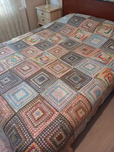 a bed with a multicolored bedspread on top of it next to a night stand