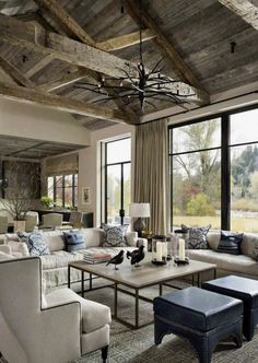 a living room filled with lots of furniture next to large windows and a chandelier