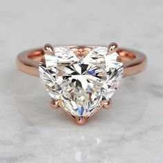 an engagement ring with a heart shaped cut diamond in the center and rose gold band