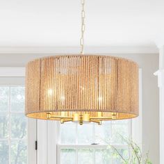 a chandelier hanging from the ceiling in a living room with white walls and windows