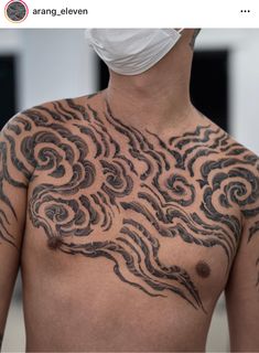 a man with tattoos on his chest wearing a face mask