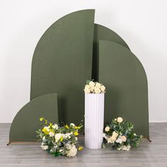 two white vases sitting next to each other on a wooden floor with flowers in front of them