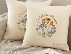 two pillows with embroidered flowers on them sitting on a couch next to a pillow case