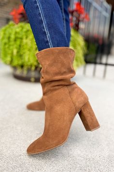 a close up of a person wearing high heeled boots and jeans with their feet in the air