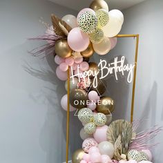 a birthday cake with balloons and feathers on the top, in front of a mirror