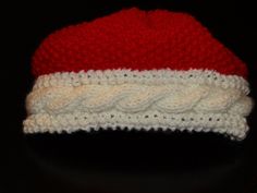 a red and white knitted hat sitting on top of a table