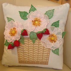 a white pillow with flowers and strawberries on the front is sitting on a chair