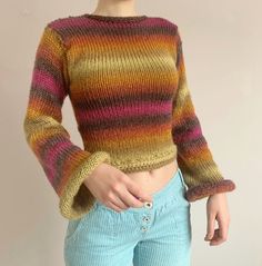 a woman wearing a multicolored sweater and blue jeans with her hands in her pockets