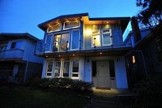 a two story house lit up at night with lights on the front and side windows