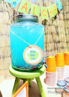 a blue jar sitting on top of a green chair next to orange and yellow cups