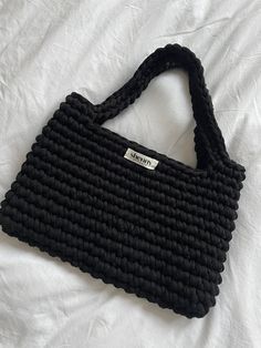 a black purse sitting on top of a white sheet