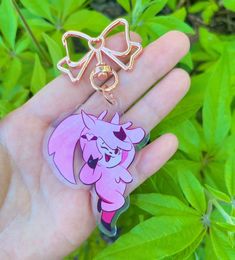 a hand holding a pink cartoon character keychain