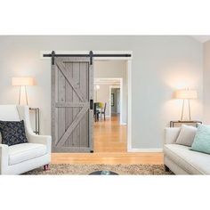 a living room with two white couches and a sliding barn door in the middle