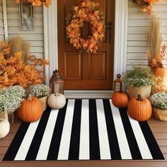 a front porch decorated with pumpkins, mumlocks and other fall decor items