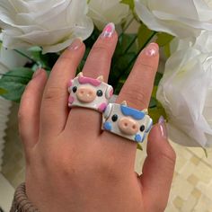 two ring shaped like cows sitting on top of each other in front of white flowers