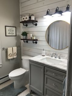 a white toilet sitting next to a sink in a bathroom under a mirror and lights