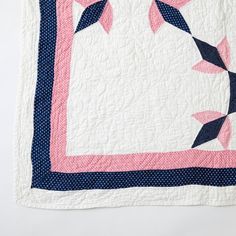 a pink and blue quilt on a white surface