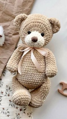 a brown teddy bear sitting on top of a bed next to a stuffed animal toy