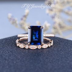 an engagement ring with a blue sapphire surrounded by white and brown diamonds, on top of a black surface