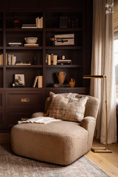 a living room filled with furniture and bookshelves next to a window covered in curtains