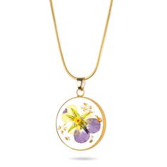 a yellow and purple flower is in the center of a circle pendant on a gold chain