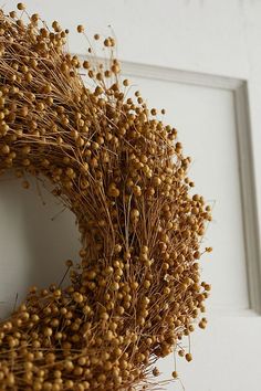 a close up of a wreath on a door with some dry grass in the middle