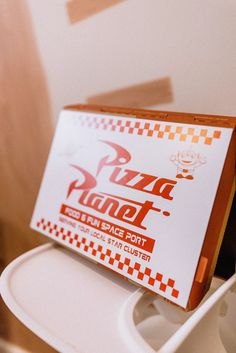 a pizza planet sign sitting on top of a toilet