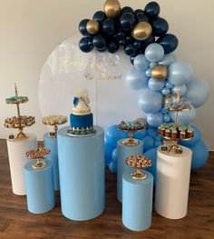 blue and white dessert table with balloons and cake on pedestals in front of it