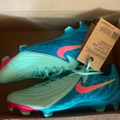 a pair of blue and pink nike soccer cleats in a box with a tag on it