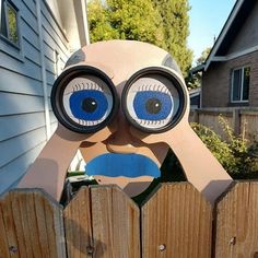 a paper cut out of a person's face behind a wooden fence with blue eyes