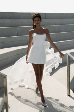 a woman in a white dress walking down some steps