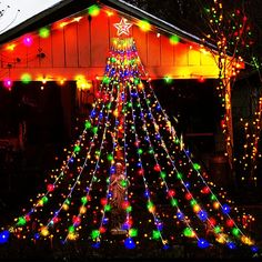 a christmas tree made out of lights in front of a house with a star on top